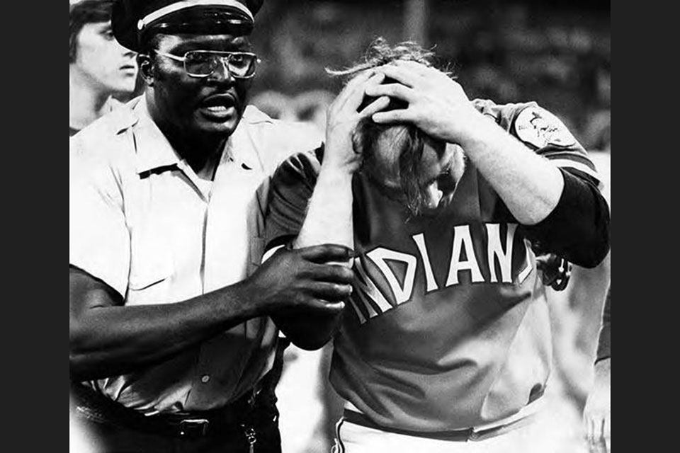 A security guard escorts Indians pitcher Tom Hilgendorf from the field. (photo courtesy of the Cleveland Press Collection, Michael Schwartz Library, Cleveland State University)