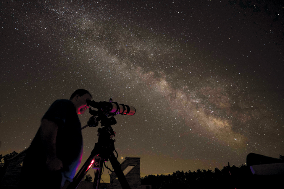 Man at JGAP looking at through a telescope at the night sky (photo by Brad Hoehne)