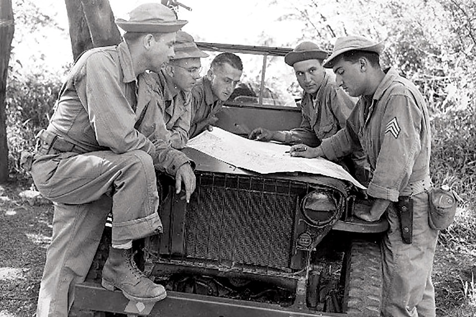 U.S. soldiers in the Pacific checking map on Willys MB slat-grille jeep