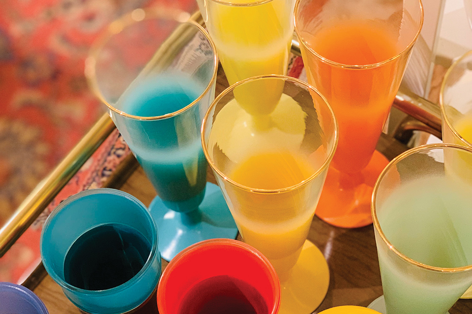 Colorful vintage glasses lined up on bar cart at Columbus‘ The Little Light Collective (photo courtesy of The Little Light Collective)