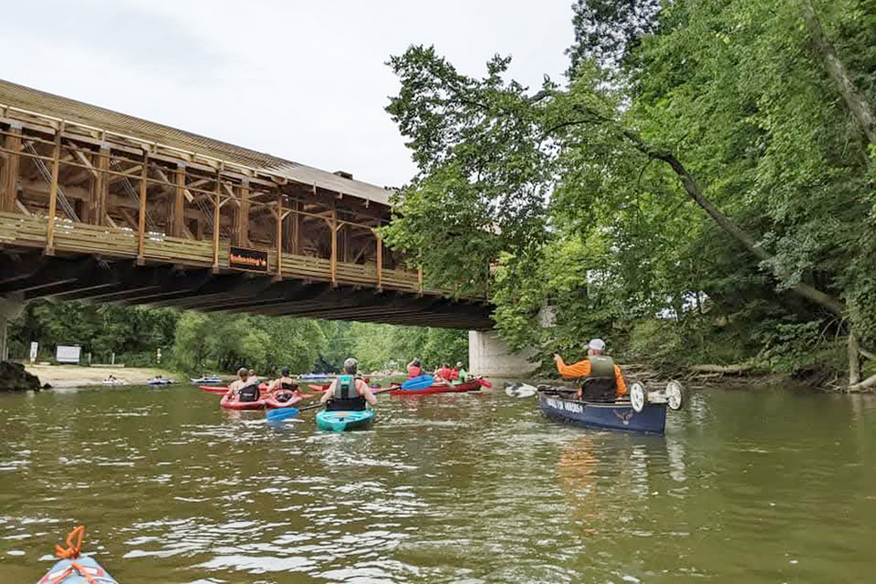 Kayakers paddle under the Spellacy Covered Bridge along the Wally Road Scenic Byway (photo courtesy of Wally Road Scenic Byway Facebook page)
