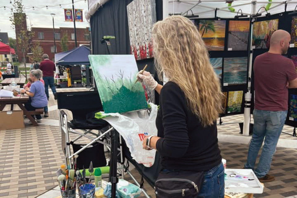 Woman painting at River of Arts Festival in Fremont (photo courtesy of Downtown Fremont Inc.)