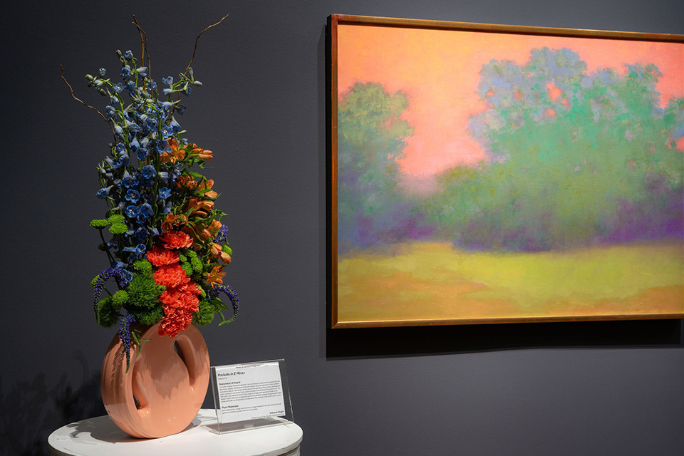 A floral arrangement next to ”Prelude in E Minor” by Richard Mayhew from Art in Bloom 2025 (photo courtesy of Cincinnati Art Museum)