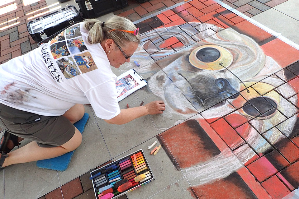 Woman creating chalk art at Art on the Canal Art Stroll (photo courtesy of Art on the Canal Art Stroll)