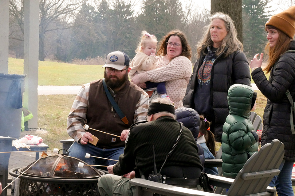 People roasting marshmallows around a fire pit in Walnut Woods Metro Park (photo by Liz Christian; courtesy of Franklin County Metro Parks)